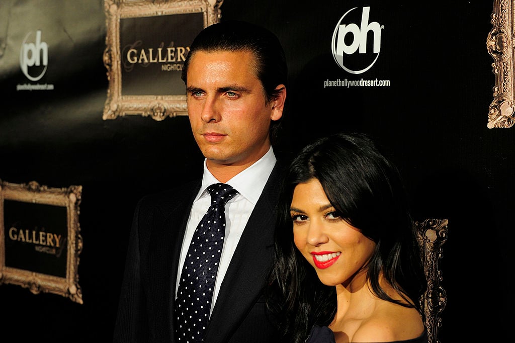 Scott Disick and Kourtney Kardashian in front of a repeating background