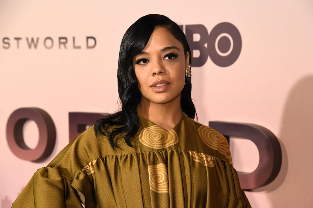 Tessa Thompson smiling in front of a repeating background