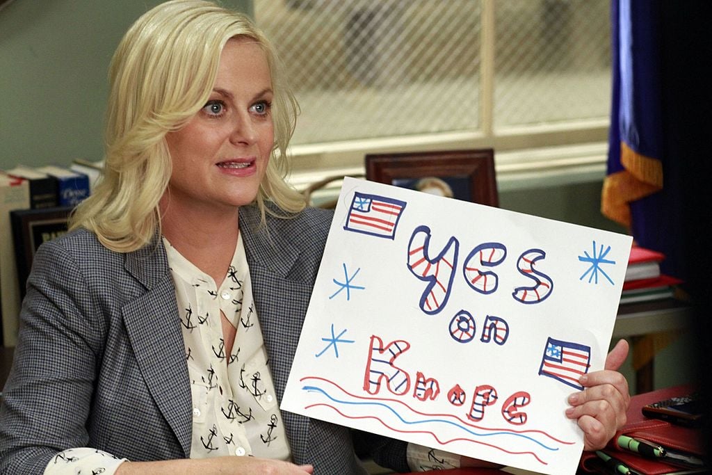 Amy Poehler as Leslie Knope holds up a sign that reads, "Yes on Knope," in 'Parks and Recreation' Season 4.