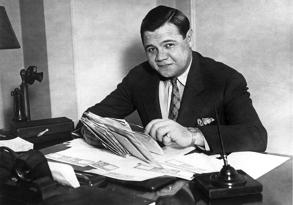 Babe Ruth smiling while opening letters, image in black and white