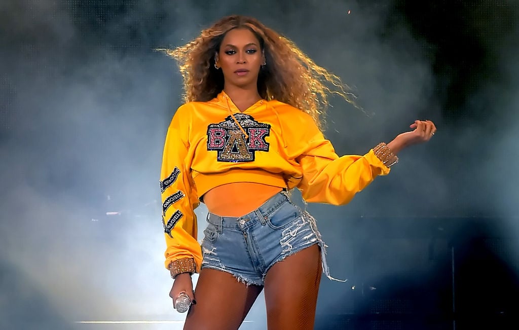 Beyoncé on stage in a yellow cropped sweatshirt and denim shorts