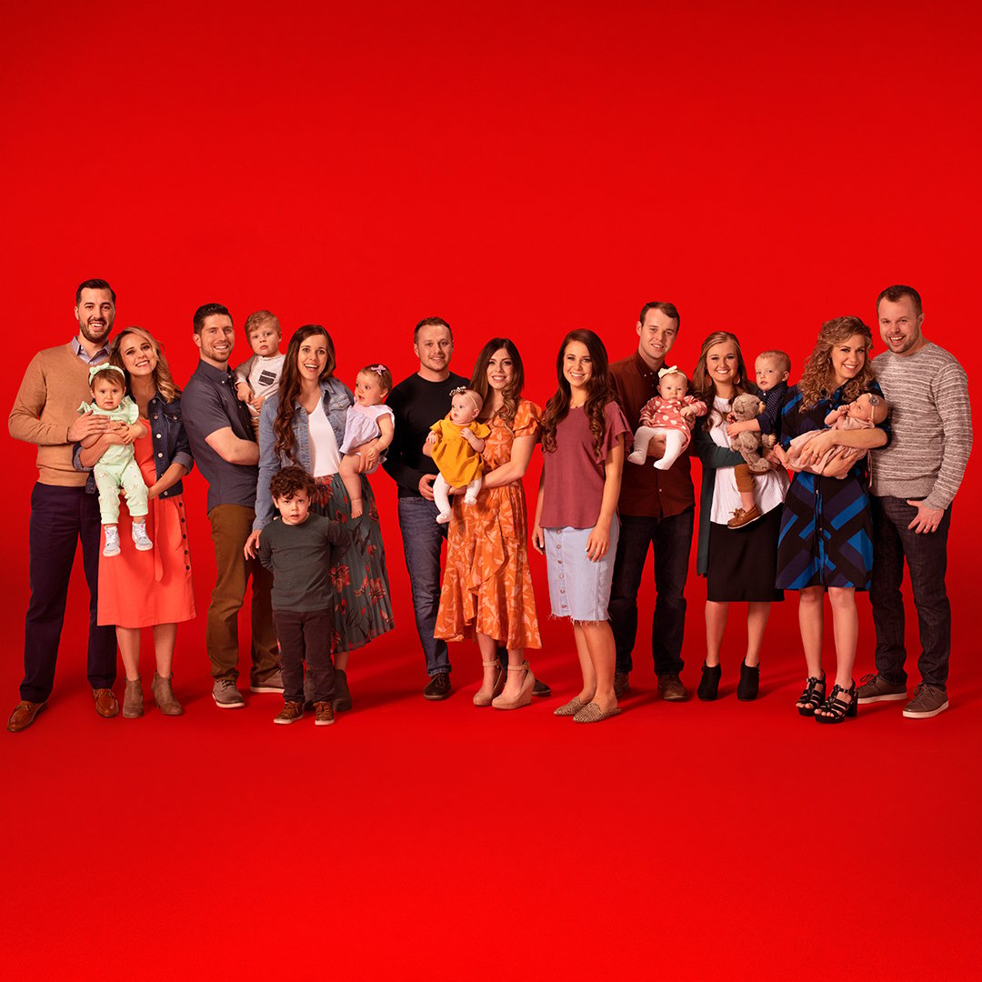 Group photo of Duggar family children and grandchildren on a red background.