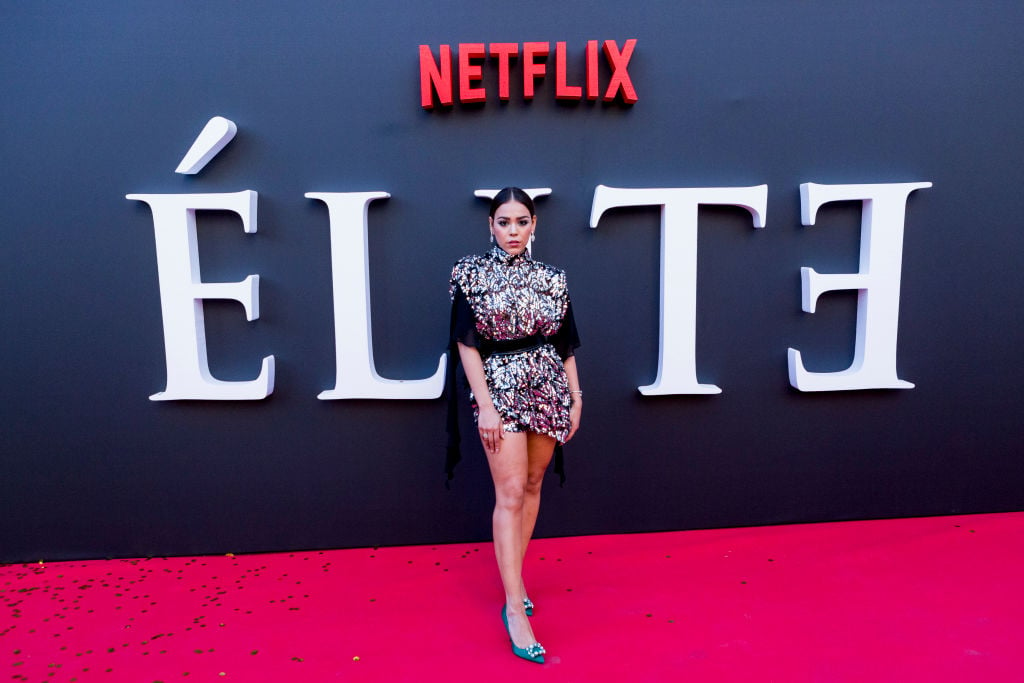 Danna Paola smiling on the red carpet in front of an 'Elite' background