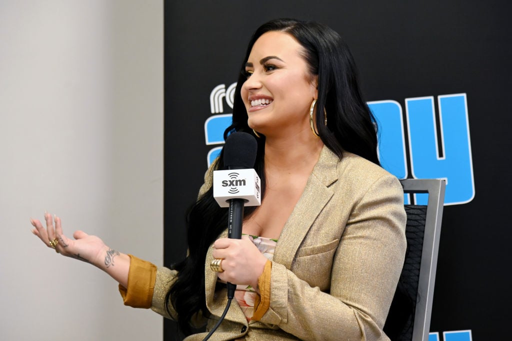 Demi Lovato smiling, holding a microphone, sitting down