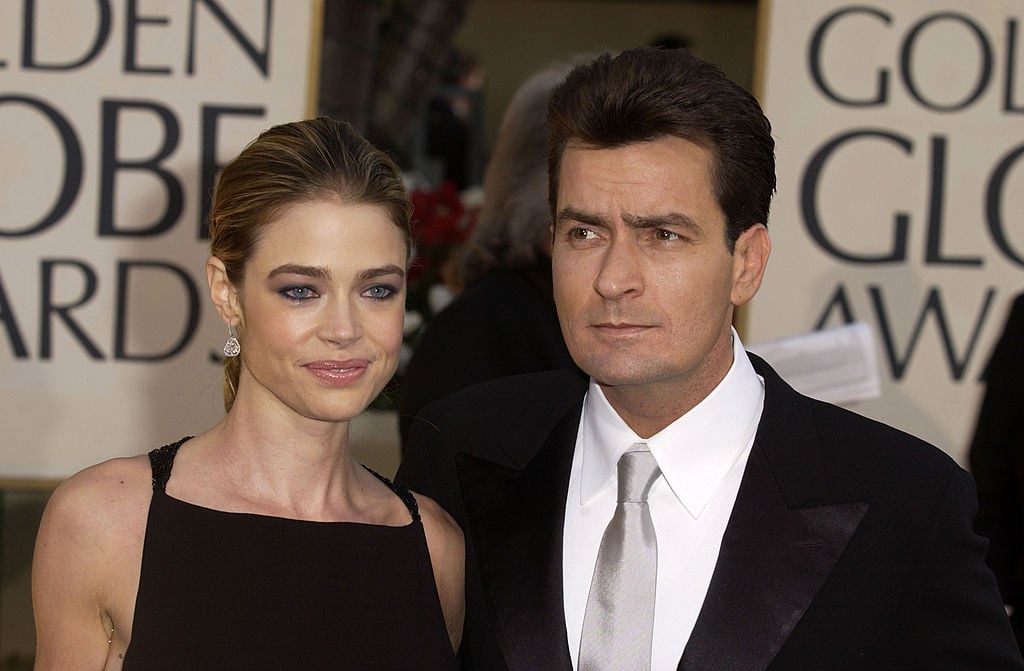 Denise Richards smiling, standing next to Charlie Sheen who is looking in the opposite direction