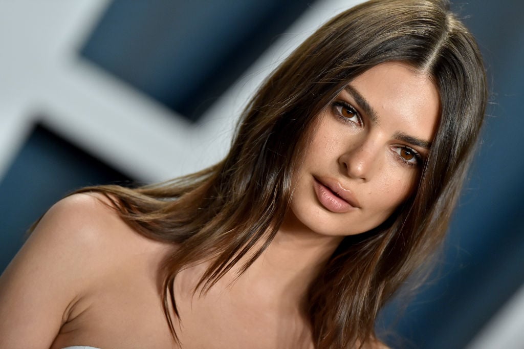 Emily Ratajkowski not smiling with her hair down wearing a sleeveless dress