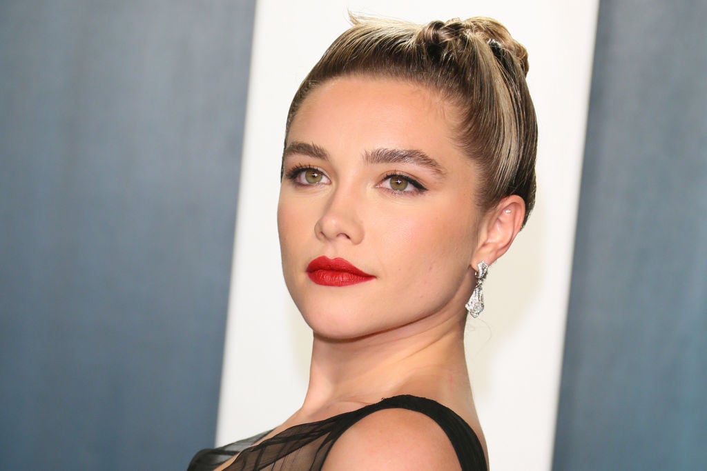 Florence Pugh slightly smiling in front of a blue and white background