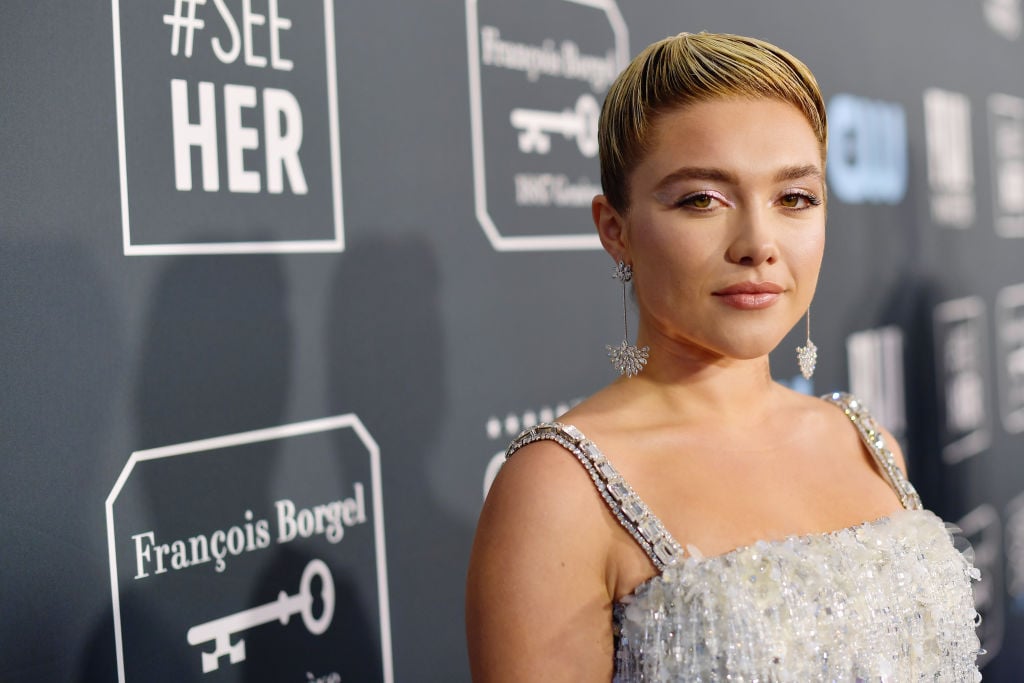 Florence Pugh smiling slightly turned slightyy toward the camera