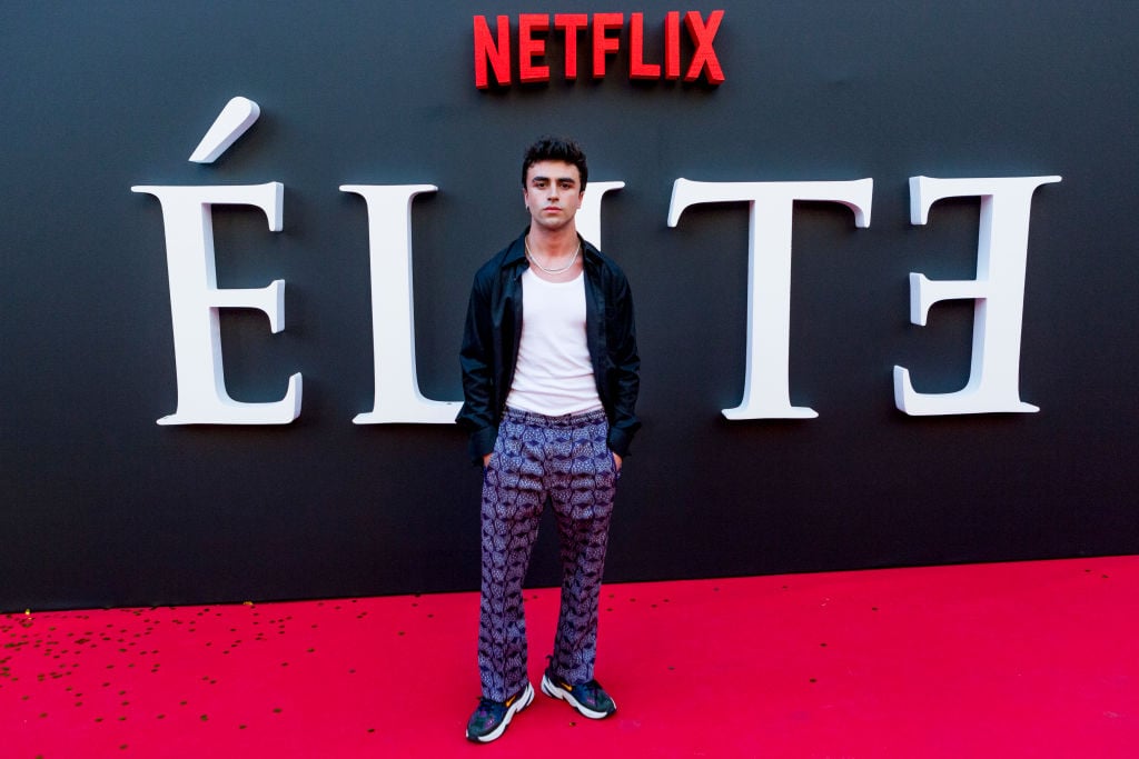 Itzan Escamilla standing in front of an 'Elite' logo not smiling with his hands at his hands