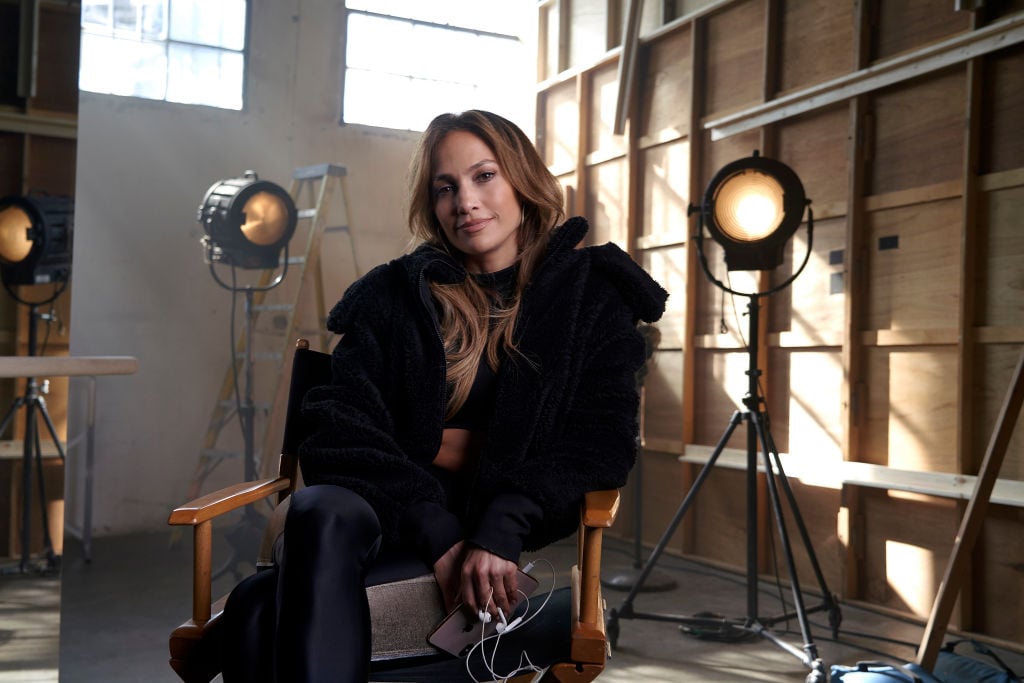 Jennifer Lopez sitting in a chair smiling at the camera wearing all black