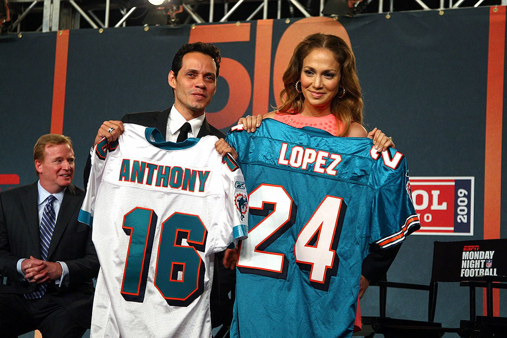 Jennifer Lopez and Marc Anthony holding up Miami Dolphins uniforms