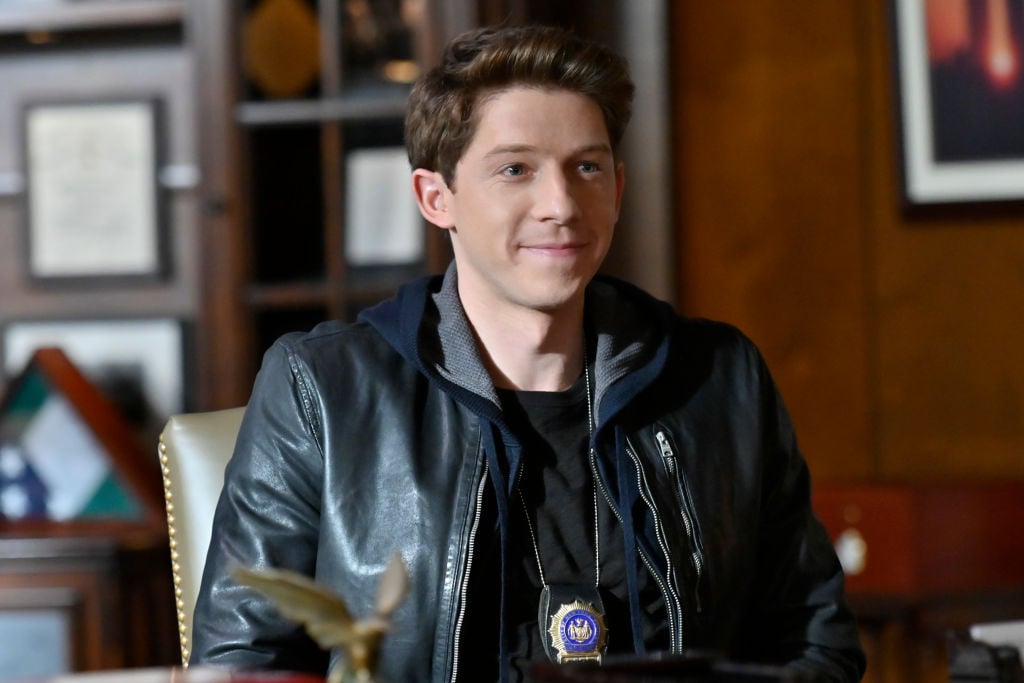 Will Hochman as Joe Hill smiling with a police badge on