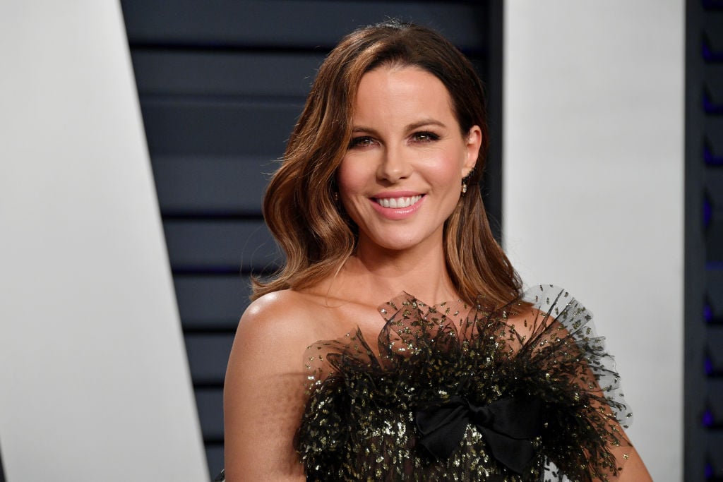 Kate Beckinsale smiling in a black and gold dress