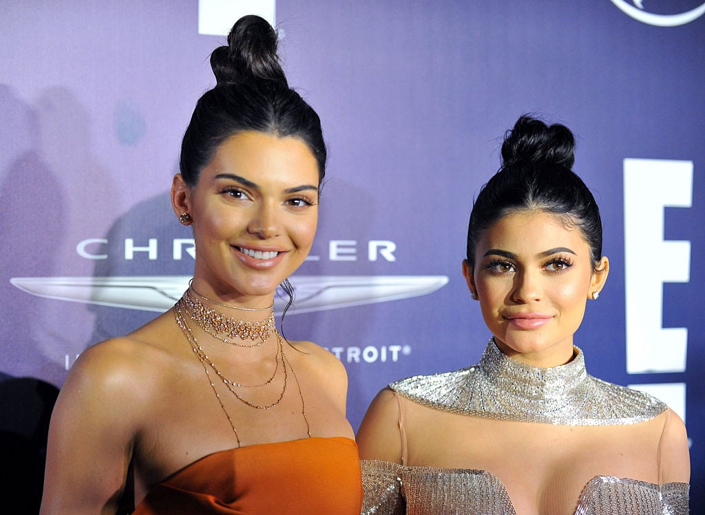 Kendall Jenner and Kylie Jenner smiling in front of a blue background