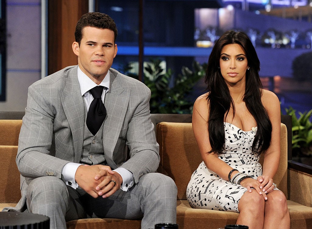 Kris Humphries and Kim Kardashian sitting on a couch, not smiling