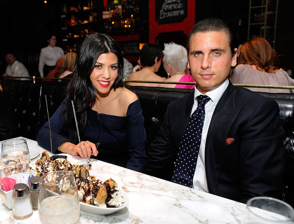 Kourtney Kardashian and Scott Disick smiling sitting at a table