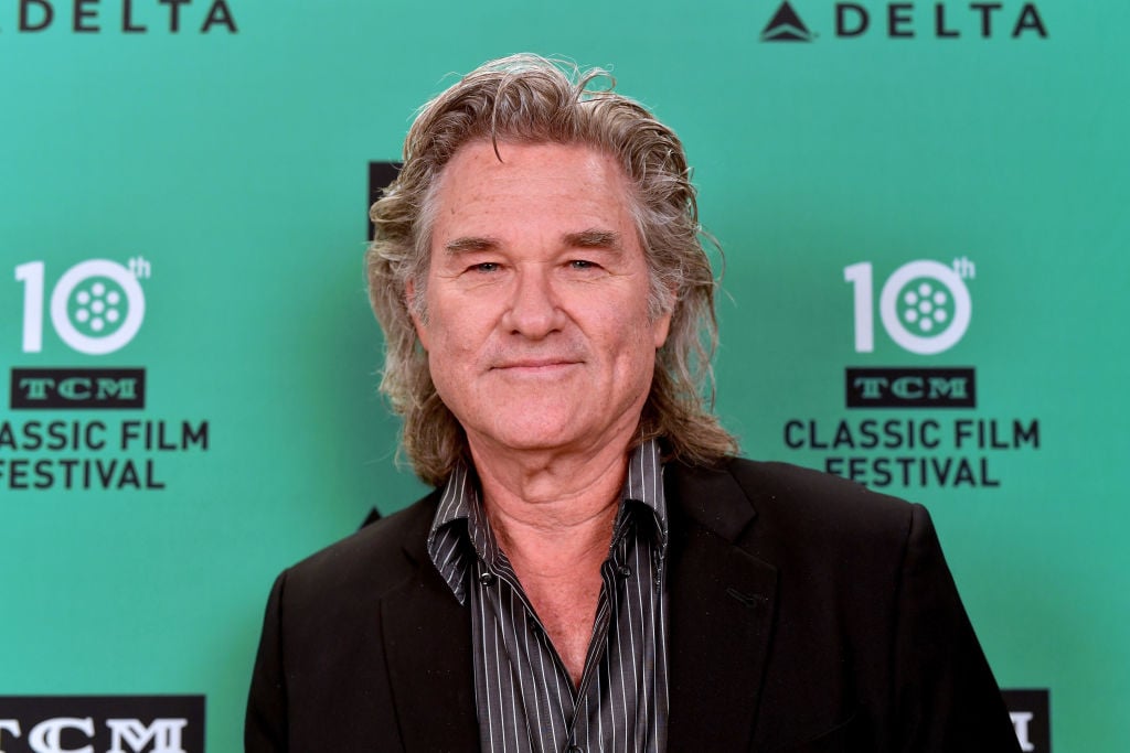 Kurt Russell smiling in front of a repeating background