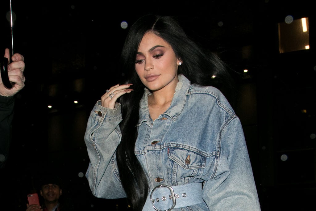 Kylie Jenner looking down wearing a jean jacket