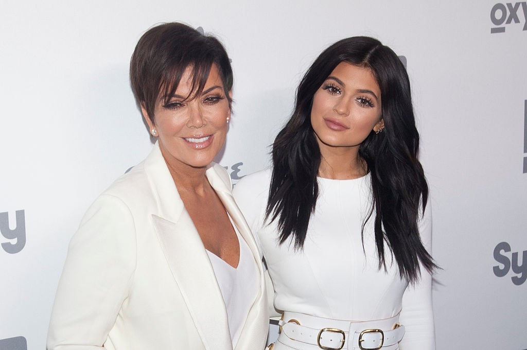Kris Jenner and Kylie Jenner smiling wearing white in front of a white backdrop