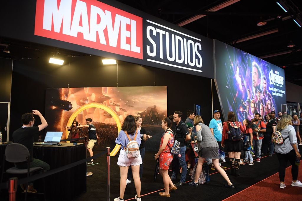 Marvel Studios banner over an entrance with groups of fans at a Disney fan event