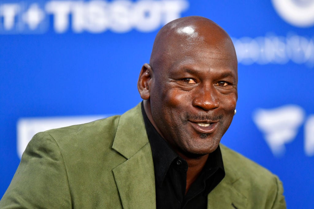 Michael Jordan smiling in front of a blue and white background