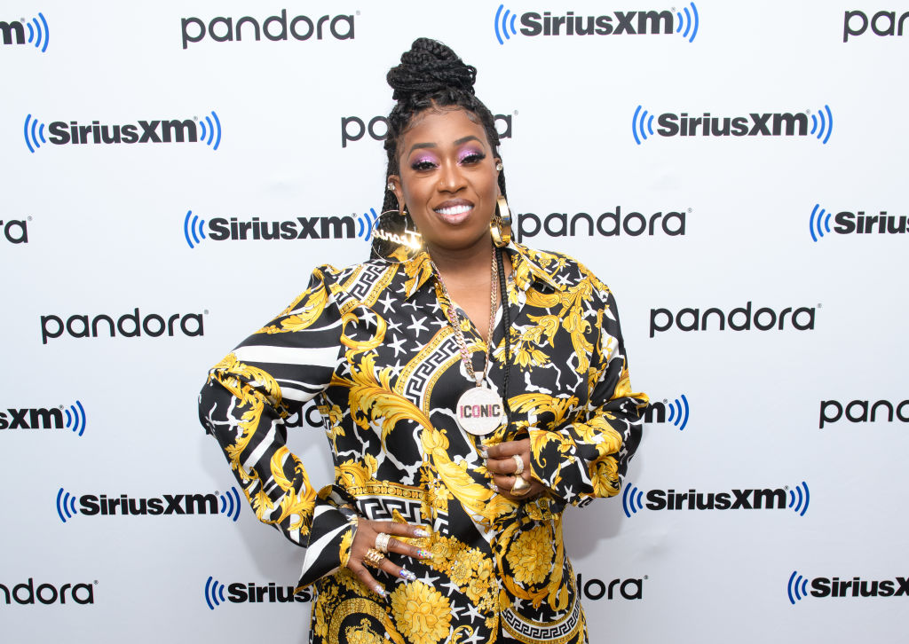 Missy Elliott smiling in front of a white and black repeating background
