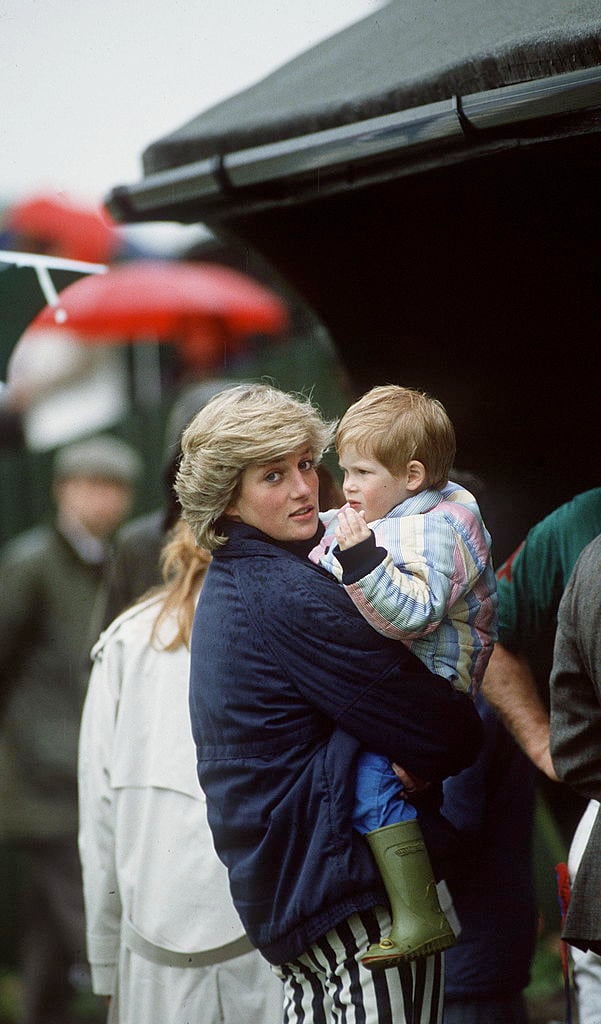Princess Diana holds a young Prince Harry in her arms at a polo match