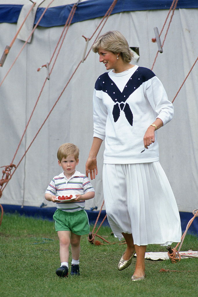 Princess Diana walks with Prince Harry as he holds a plate of strawberries