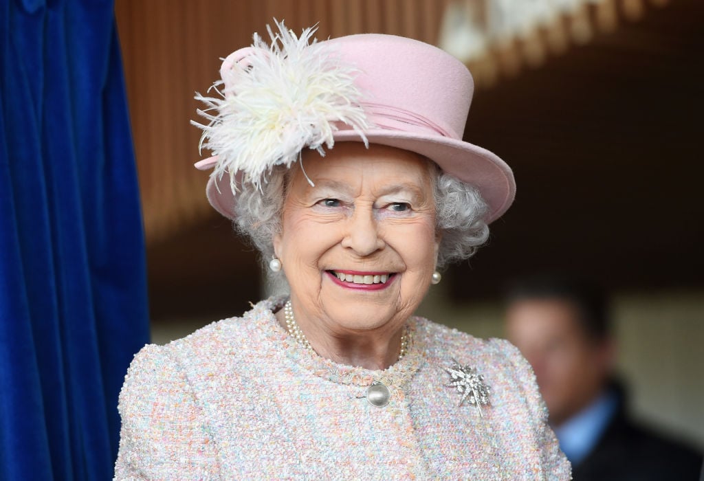 Queen Elizabeth II smiling wearing a pink suit