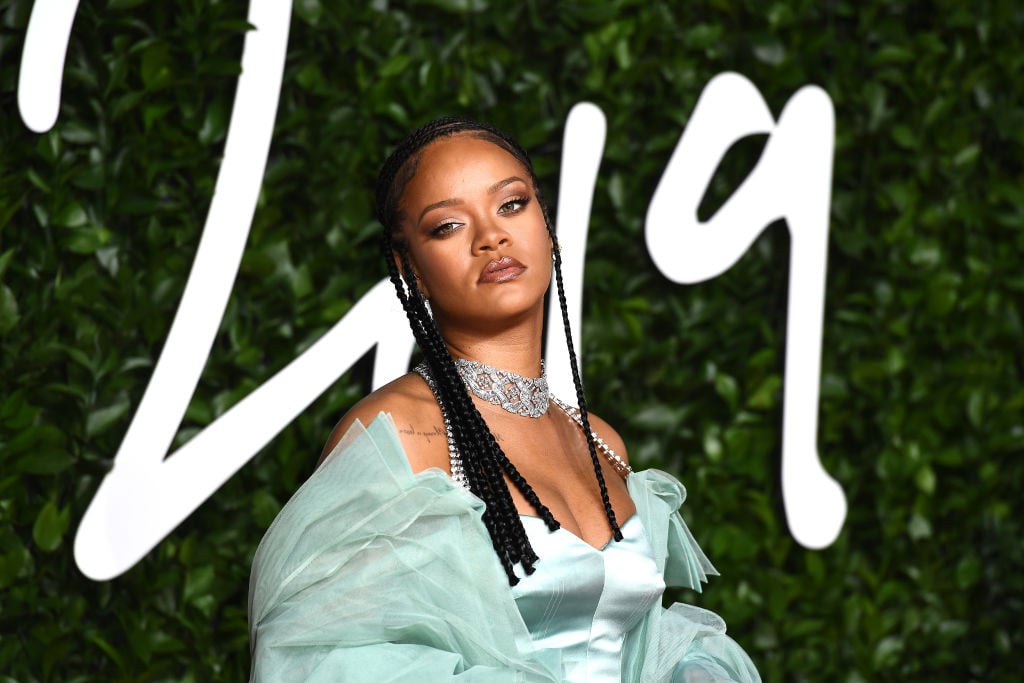 Rihanna in light blue looking slightly off camera in front of a green background