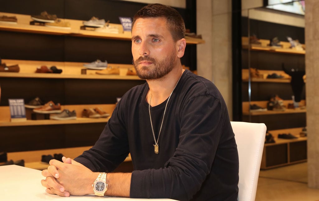 Scott Disick sitting with his hands folded, looking away from the camera