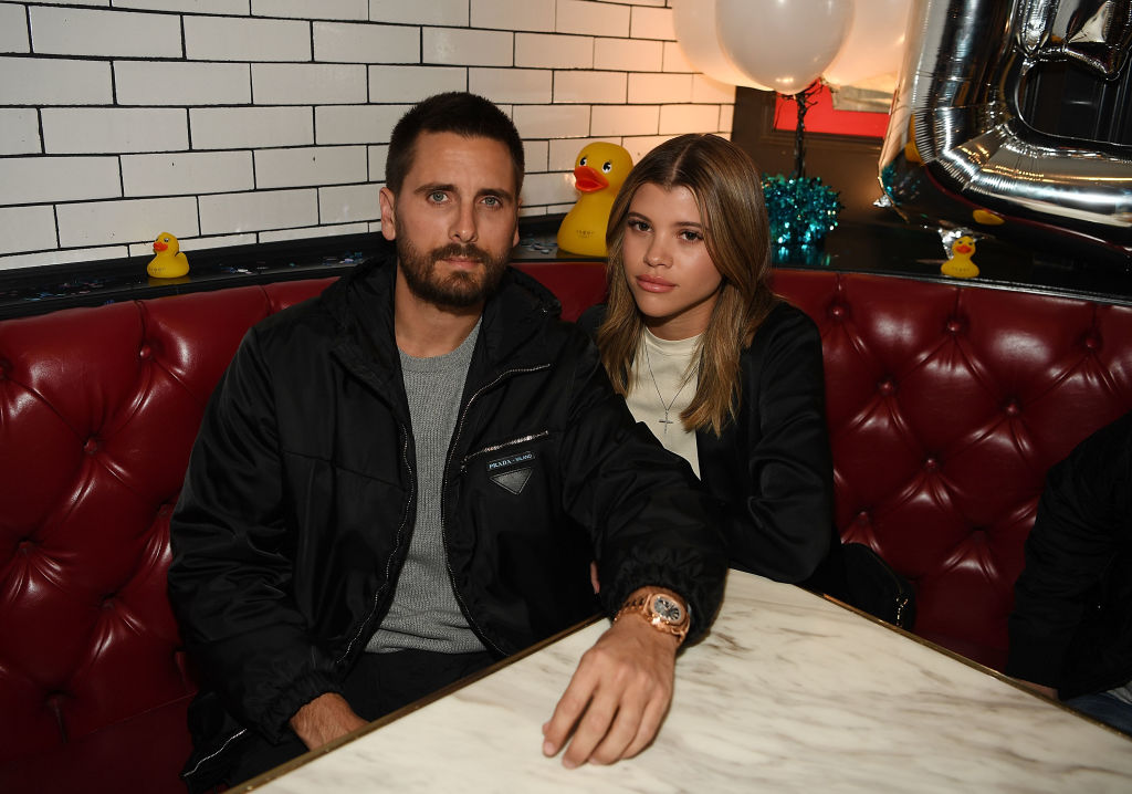 Scott Disick and Sofia Richie smiling sitting at a table