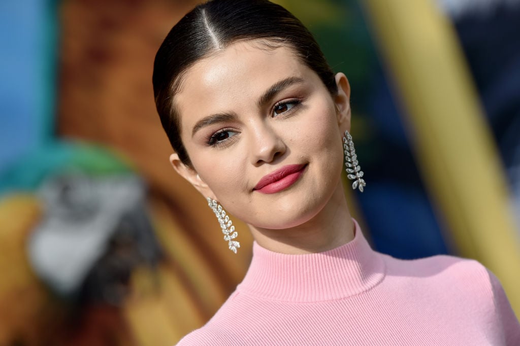 Selena Gomez smiling in a pink turtleneck