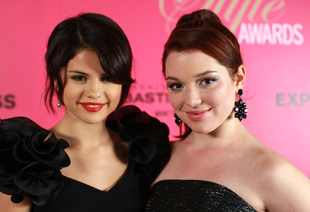 Selena Gomez and Jennifer Stone smiling in front of a pink background