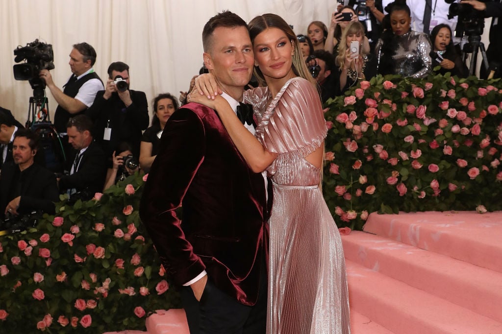 Tom Brady and Gisele Bundchen embracing, smiling at a camera to the side