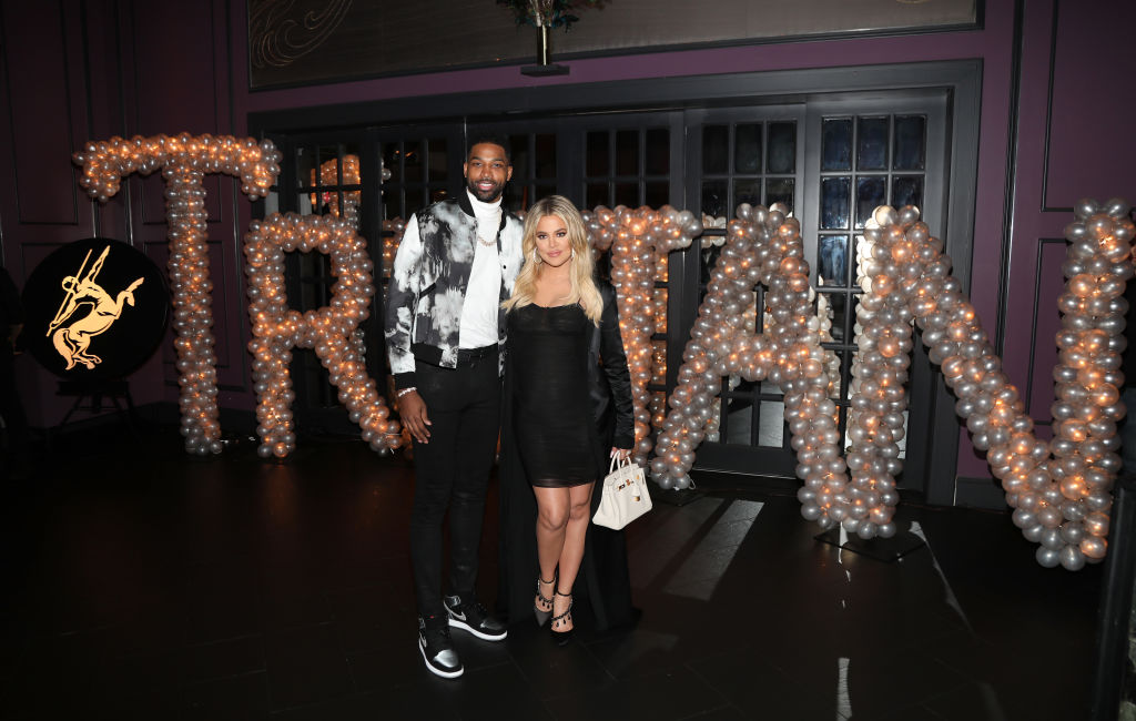 Tristan Thompson and Khloé Kardashian smiling in front of a balloon display