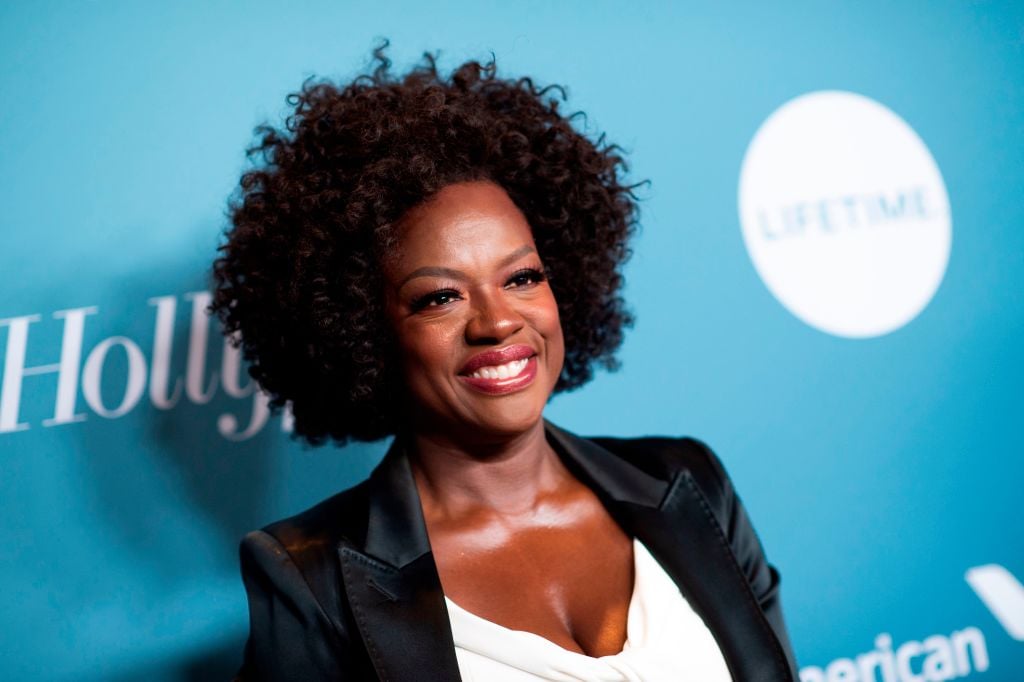 Viola Davis smiling in front of a repeating blue background
