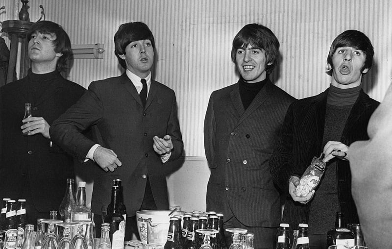 The Beatles at a table stocked with beer