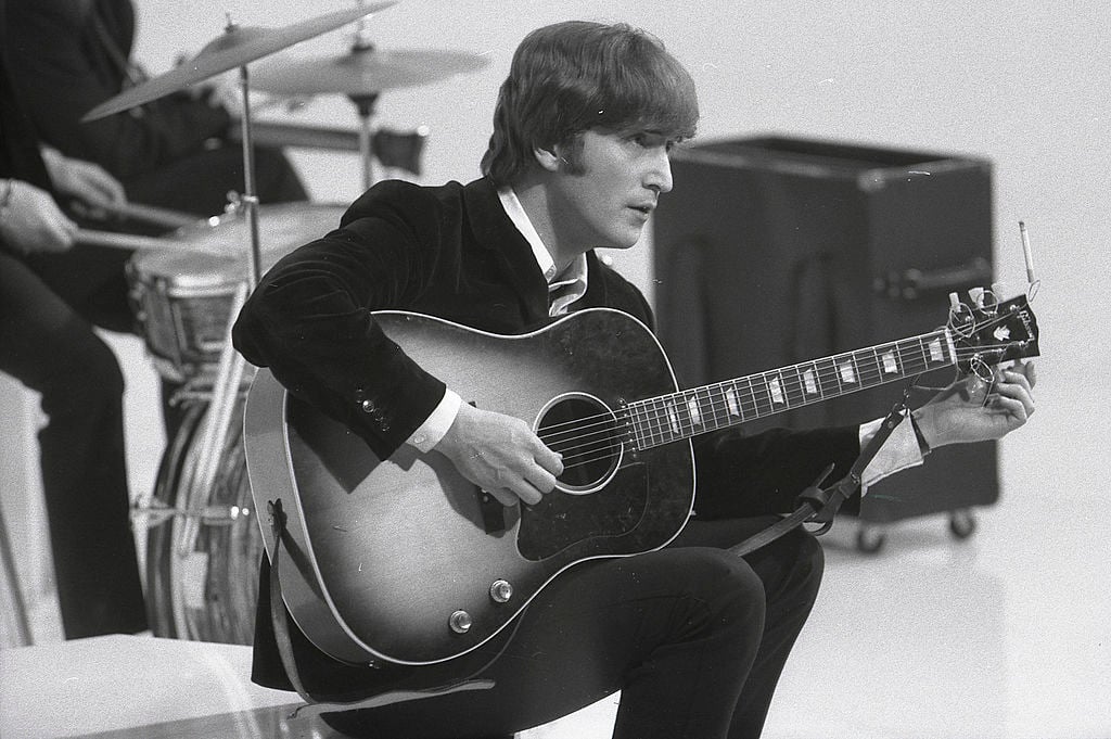 John Lennon of The Beatles sitting with his guitar