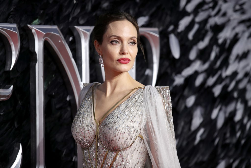 Angelina Jolie looking away from the camera in a light gray dress with beading