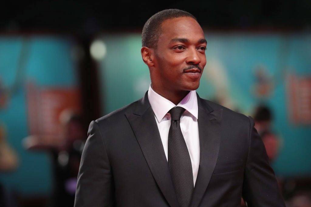 Anthony Mackie smiling, looking off camera, wearing a suit