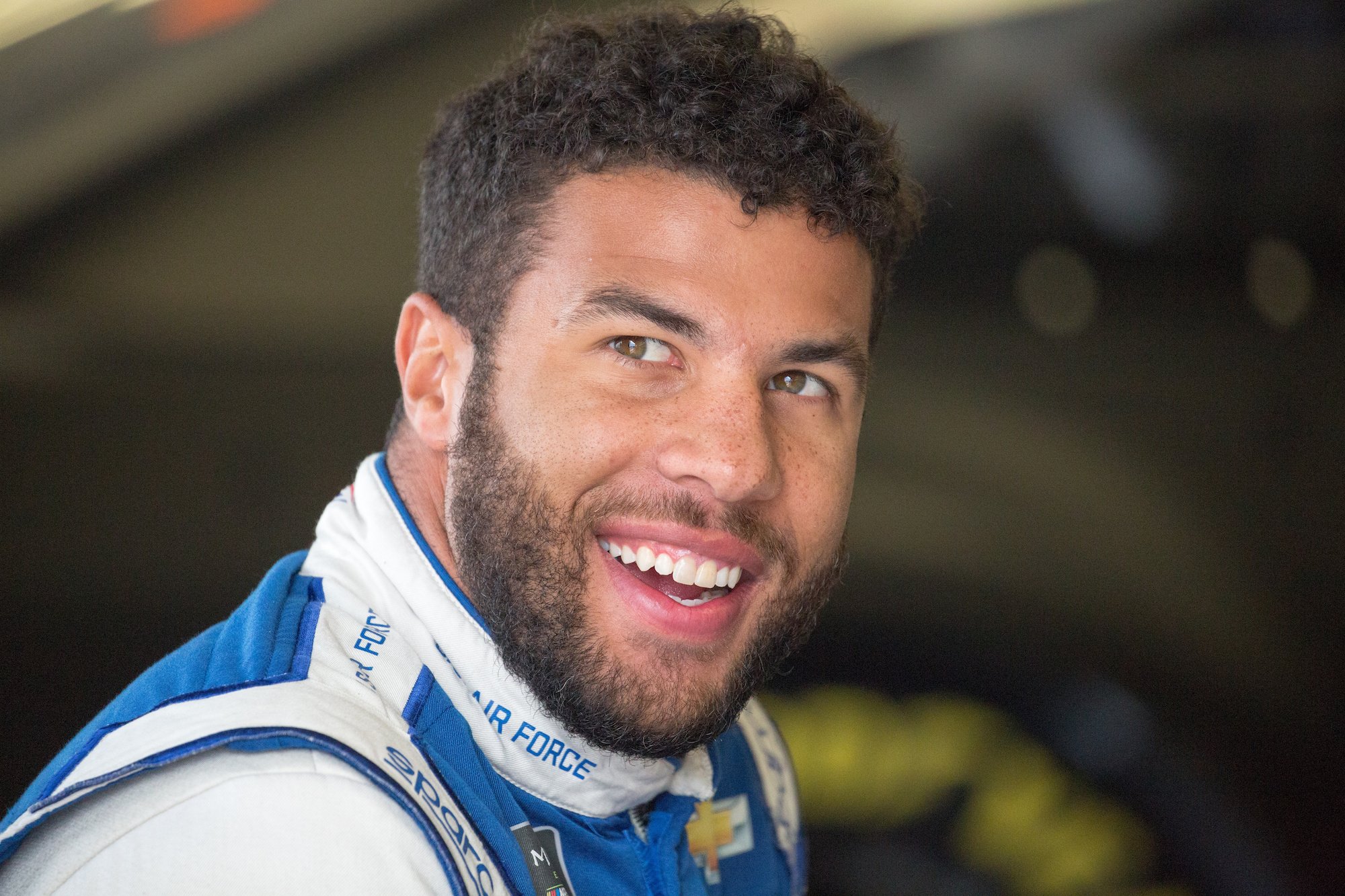 Bubba Wallace smiling, looking to the side of the camera