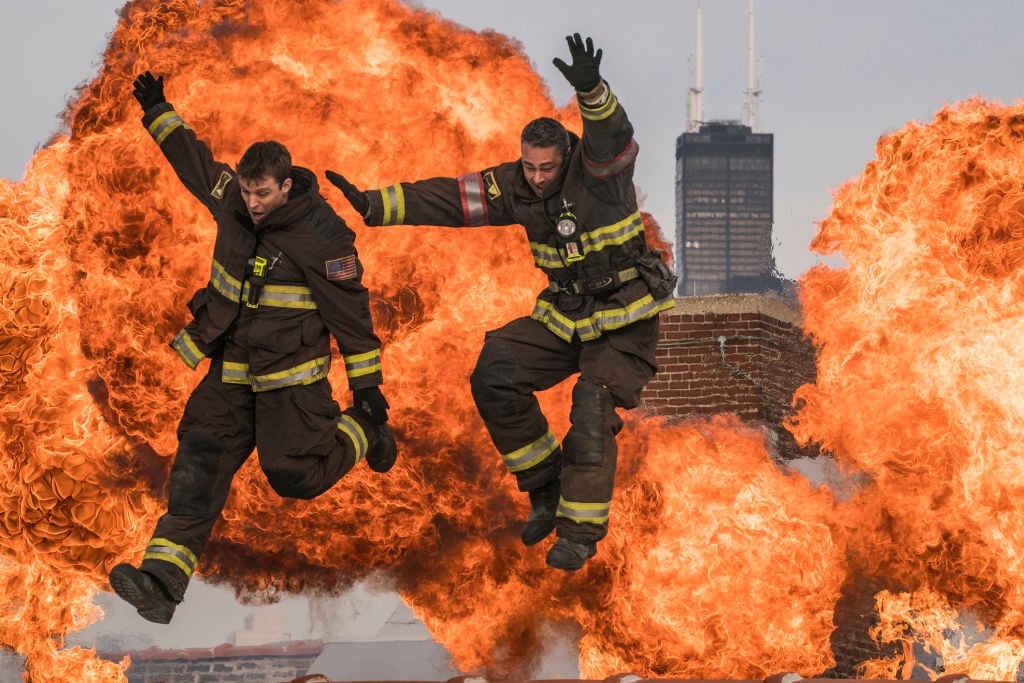 Jesse Spencer as Matthew Casey, Taylor Kinney as Kelly Severide jumping in front of large clouds of fire
