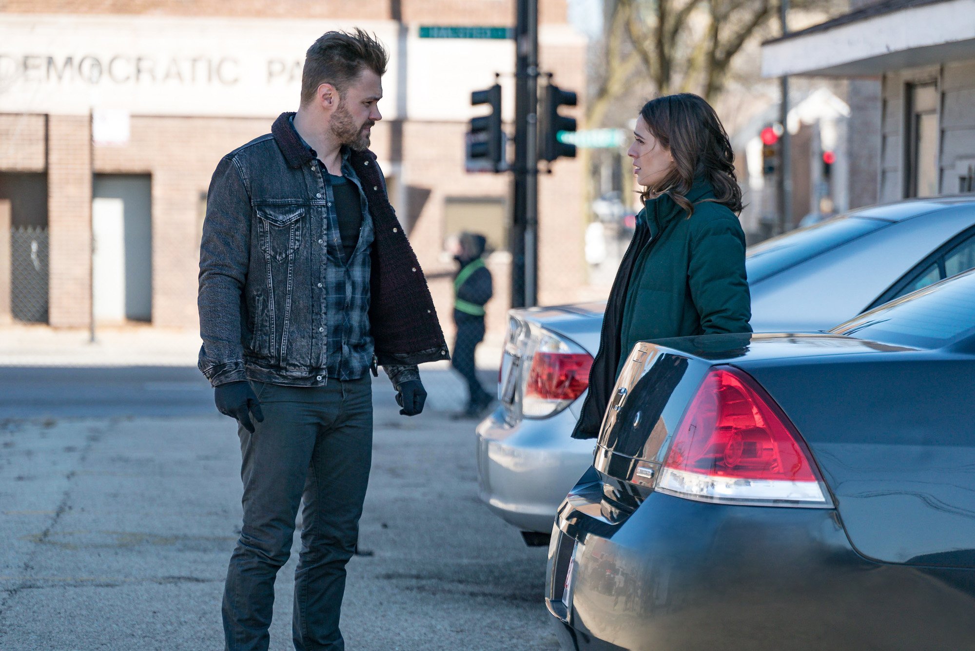 Patrick John Flueger as Adam Ruzek, Marina Squerciati as Kim Burgess turned to the side, facing each other in a parking lot