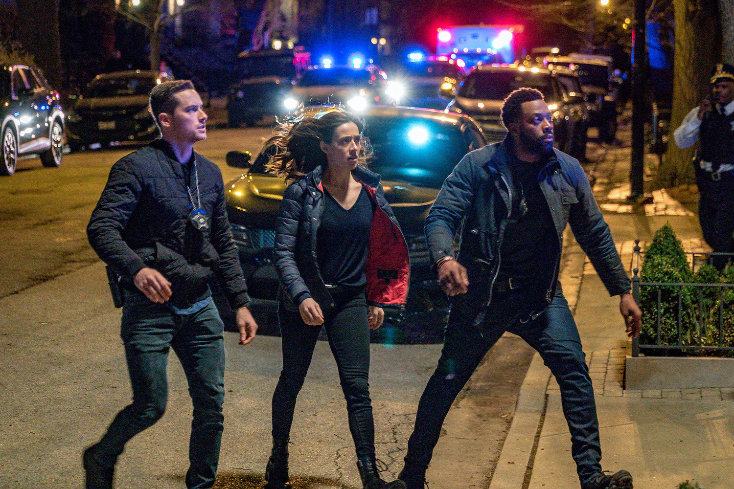 Jesse Lee Soffer as Det. Jay Halstead, Marina Squerciati as Officer Kim Burgess, LaRoyce Hawkins as Officer Kevin Atwater walking outside in front of several police cars with lights on