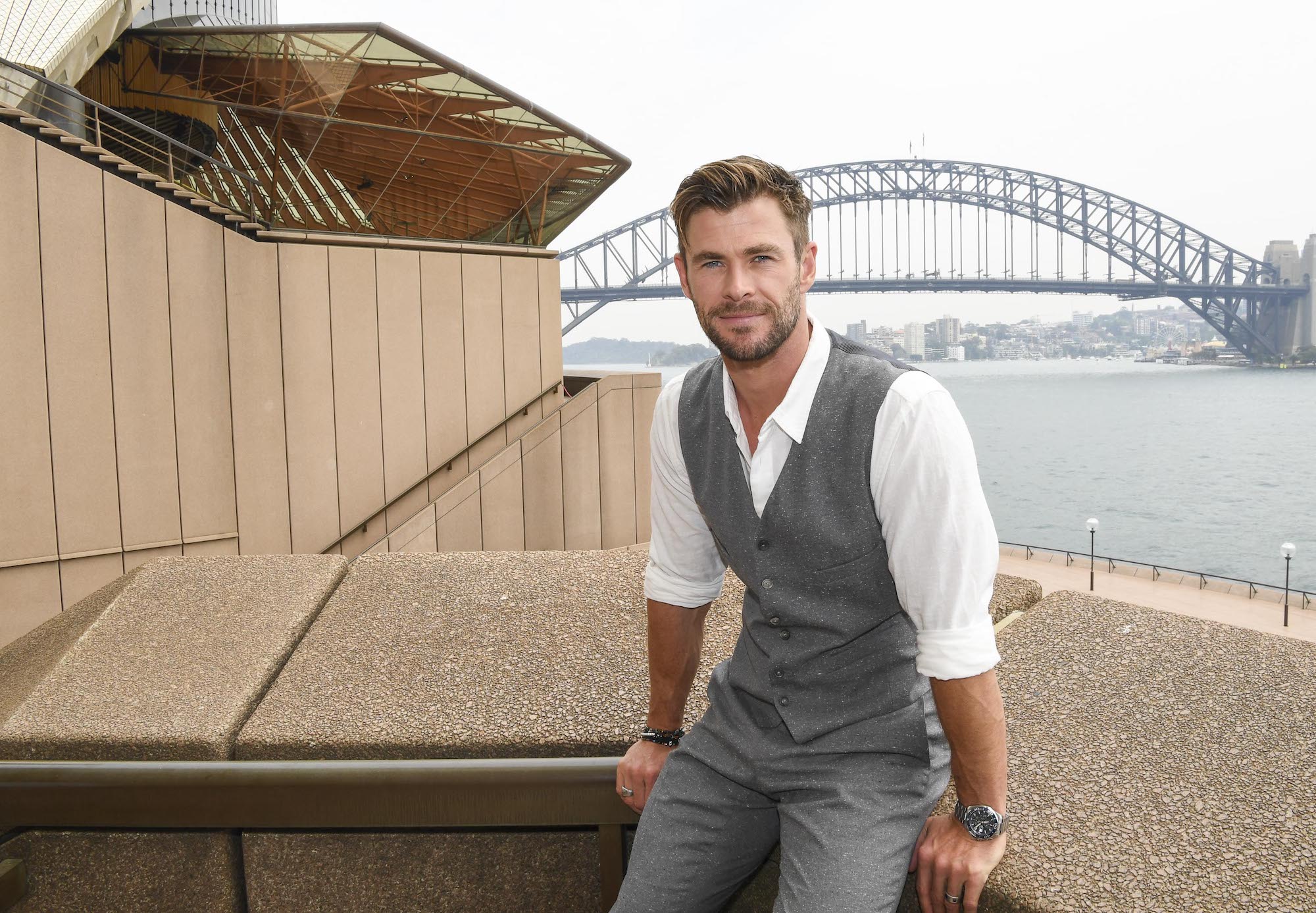 Chris Hemsworth smiling in front of a bridge