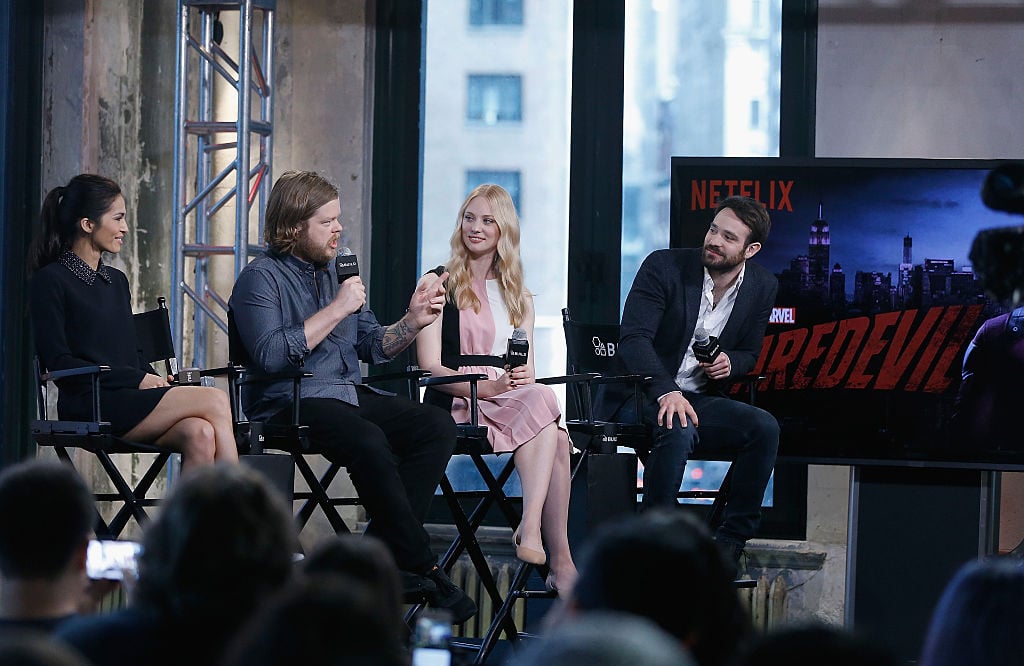 Elodie Yung, Elden Henson, Deborah Ann Woll and Charlie Cox speaking on a stage next to a screen with the 'Daredevil' logo