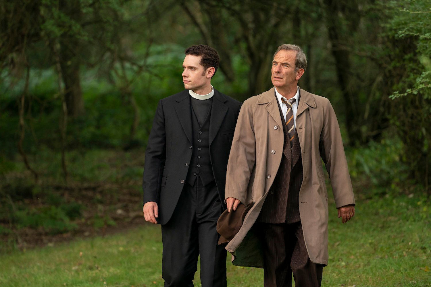 Tom Brittney as Will Davenport, wearing priest's collar, and Robson Green as Geordie Keating, wearing tan jacket, in 'Grantchester' 