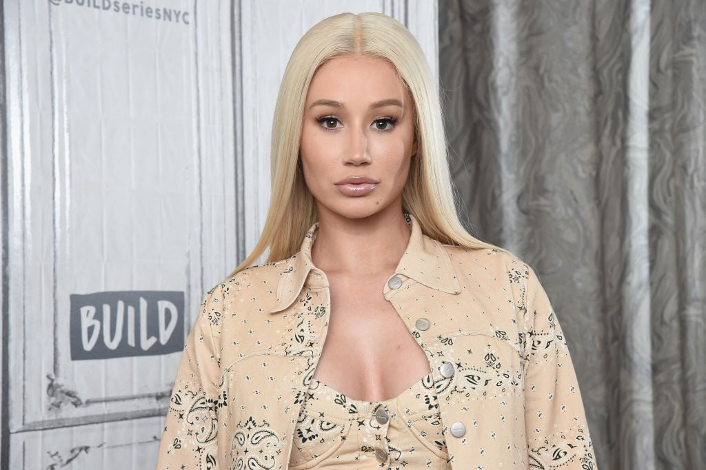 Iggy Azalea slightly smiling in front of a white and light gray background