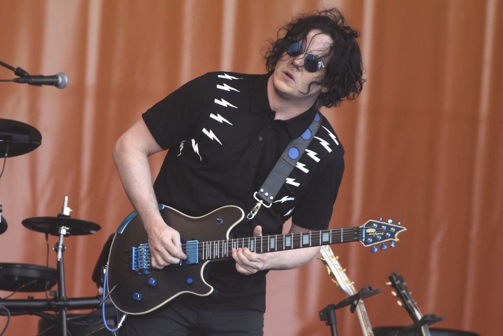 Jack White playing guitar on stage wearing sunglasses